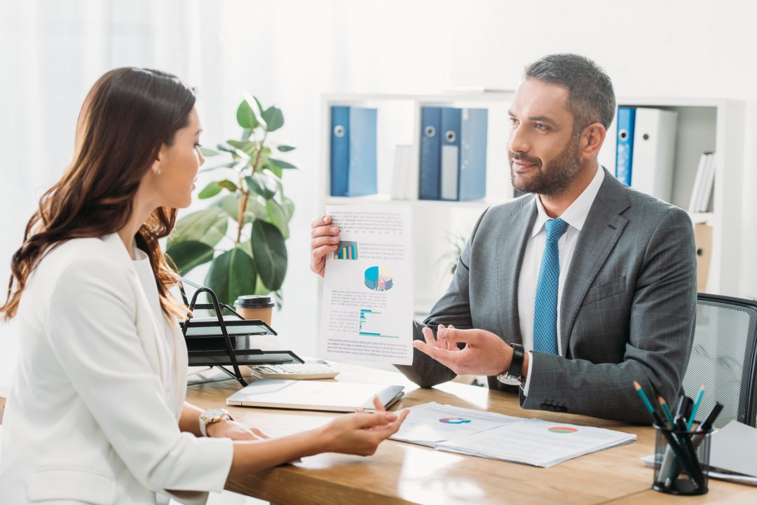 handsome advisor discussing document with investor at office